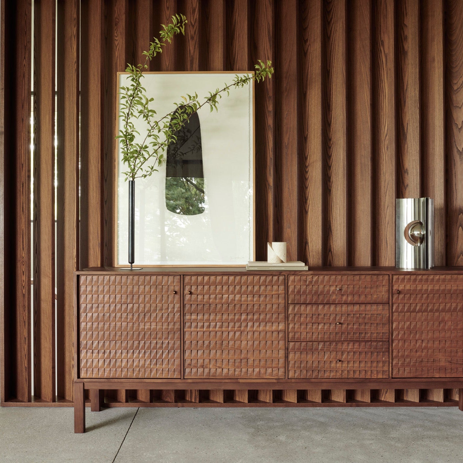 Wooden cabinet with a mirror and decorative items against a wooden paneled wall.
